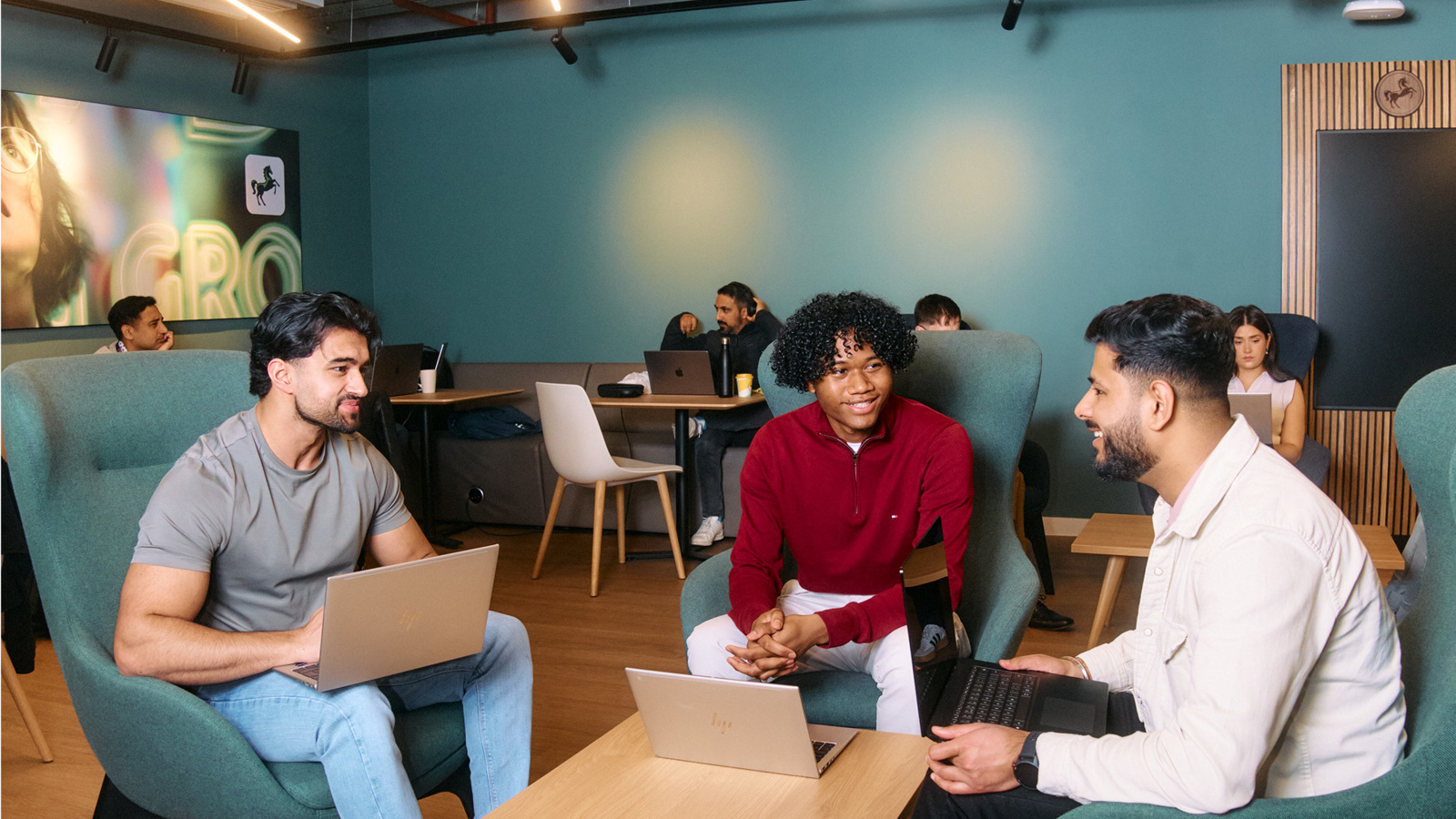 a group of men sitting in chairs with laptops